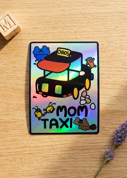 Holographic sticker of a 'Mom Taxi' with whimsical animals acting like toddlers on a wooden surface.