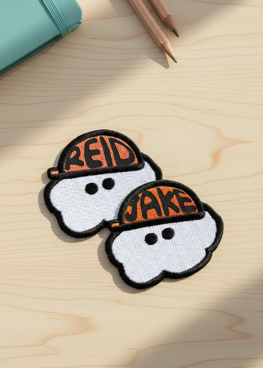 Two cloud-shaped patches with 'Red' and 'Jake' text on a wooden surface.